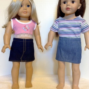 K&ouml;nnte beinhalten: Zwei Puppen in Jeansr&ouml;cken und Oberteilen. Eine Puppe hat blondes Haar und ein rosa Oberteil mit Schmetterlingsmuster und Spitzenbesatz. Die andere Puppe hat braunes Haar und ein gestreiftes Oberteil.