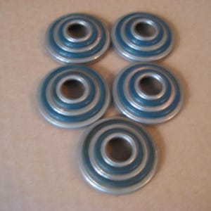 May include: Five round, silver-colored, decorative knobs with blue concentric circles. The knobs have a hole in the center.