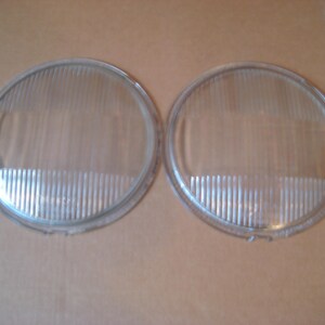 May include: Two clear glass round headlight lenses with a ribbed pattern.