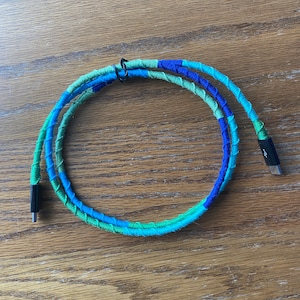 May include: A blue, green, and turquoise braided charging cable with black USB-C connectors.