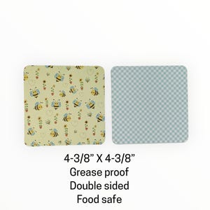 May include: Two square coasters, each measuring 4-3/8 inches by 4-3/8 inches. One coaster features a light yellow background with bees, sunflowers, and hearts. The other has a blue and white checkered pattern. The text reads: Grease proof, Double sided, Food safe.
