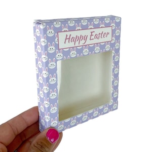 May include: A purple gift box with a clear window, featuring a repeating pattern of white bunnies with pink ears and noses. The box has the text "Happy Easter" printed on the front.