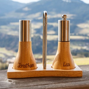 Può includere: Un set di saliera e pepe in legno con un top in metallo e un supporto. Le saliere sono incise con i nomi "Jonathan" e "Lisa".
