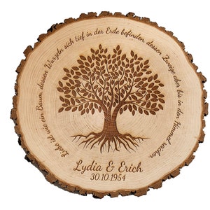 Op de afbeelding: Een houten boomschijf met een gegraveerd boomontwerp en de tekst "Liebe ist wie ein Baum, dessen Wurzeln sich tief in der Erde befinden, dessen Zweige aber bis in den Himmel reichen." De namen "Lydia & Erich" en de datum "30.10.1954" zijn ook in het hout gegraveerd.