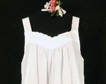 May include: A white cotton nightgown with a scalloped neckline and thin straps.