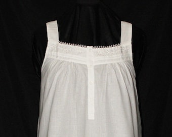 May include: A white cotton nightgown with lace trim at the neckline and straps. The nightgown has a simple, classic design.