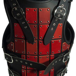 May include: A black leather armor vest with red leather plates and metal rivets. The vest has straps and buckles for adjusting the fit.