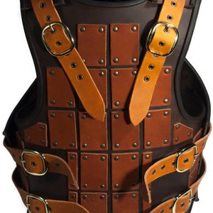 May include: A brown leather armor vest with a decorative design of square panels and metal rivets. The vest has adjustable straps with buckles.