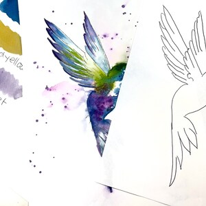 Könnte beinhalten: Ein Aquarellbild eines Kolibris im Flug mit violetten, grünen und blauen Farben. Das Bild ist auf weißem Hintergrund mit ein paar violetten Farbspritzern. Eine Linienzeichnung eines Kolibris befindet sich auf einem separaten Blatt Papier.