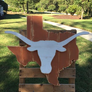 Burnt orange state of Texas wood pallet sign with an oversized white Longhorn logo in the center.