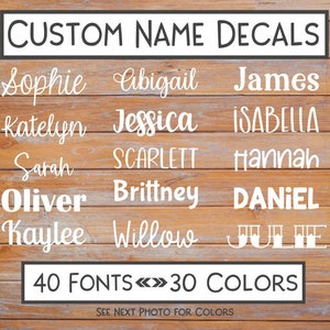 May include: White custom name decals in various fonts. Names include Sophie, Abigail, James, Katelyn, Jessica, Isabella, Sarah, Scarlett, Hannah, Oliver, Brittney, Daniel, Kaylee, Willow, and Julie. The image states "40 FONTS <> 30 COLORS".