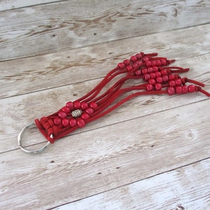 May include: Red leather keychain with a silver charm and red beads.