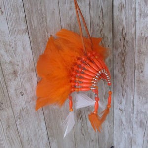 May include: Orange and white feather headdress with orange beads and a leather strap.