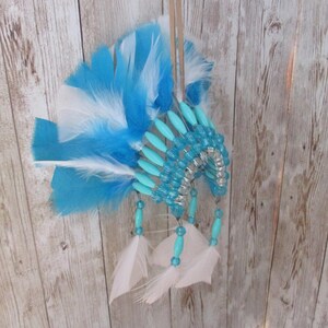 May include: A blue and white feather headdress with turquoise beads and a leather cord.
