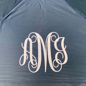 May include: A navy blue umbrella with a white monogram of the letters "A M G" in a script font.