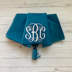 May include: A teal blue umbrella with a white monogram of the letters "SBC" in a script font.