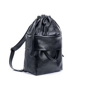 May include: A black leather drawstring backpack with a flap closure and a top handle.