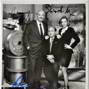 Może przedstawiać: Czarno-białe zdjęcie trzech aktorów, Gregory'ego Pecka, Danny'ego DeVito i Penelope Ann Miller, z filmu "Other People's Money". Aktorzy stoją przed ścianą z szpulami drutu.