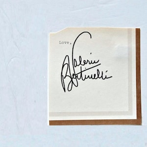 May include: A square card with a light beige background, featuring the handwritten signature "Valerie Bertinelli" in black ink. The word "Love," is printed above the signature. The card has a brown border.