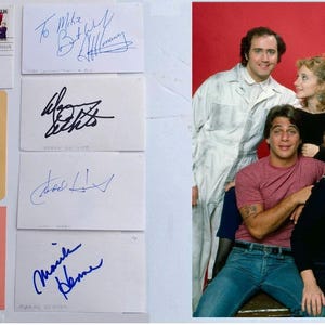 Może przedstawiać: Obraz przedstawia kolekcję podpisanych kart i zdjęcie grupowe. Karty mają różne podpisy czarnym i niebieskim tuszem. Zdjęcie grupowe przedstawia siedem osób pozujących na czerwonym tle.