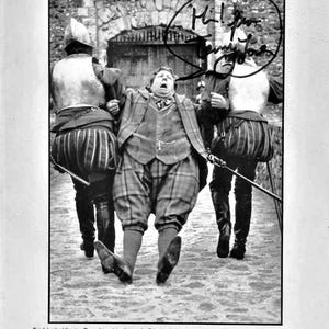 May include: A black and white photograph from "The Wind in the Willows" showing Toad being escorted by two guards. The image includes a speech bubble with handwritten text. The bottom of the image contains text about the film.