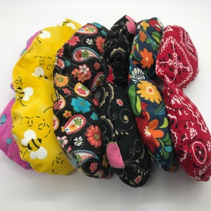 Puede incluir: Seis almohadas para ojos de tela de colores con diferentes patrones, incluyendo abejas, paisley, flores y un estampado de bandana.