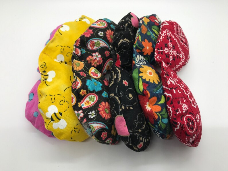 Puede incluir: Seis almohadas para ojos de tela de colores con diferentes patrones, incluyendo abejas, paisley, flores y un estampado de bandana.