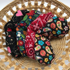 Puede incluir: Cinco bolsas de tela en forma de coraz&oacute;n en una cesta tejida. Las bolsas est&aacute;n hechas de diferentes telas con varios patrones coloridos, incluyendo paisley, floral y lunares.