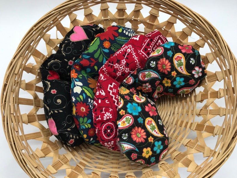 Puede incluir: Cinco bolsas de tela en forma de coraz&oacute;n en una cesta tejida. Las bolsas est&aacute;n hechas de diferentes telas con varios patrones coloridos, incluyendo paisley, floral y lunares.