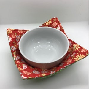 May include: A green and red floral bowl cozy with a white bowl inside.