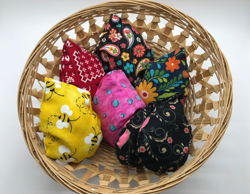 Puede incluir: Una cesta de mimbre llena de seis bolsas de frijoles de tela. Las bolsas de frijoles son de varios colores y patrones, incluyendo rojo, amarillo, rosa, negro y azul.