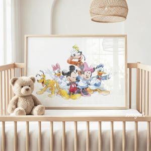 May include: Watercolor print featuring Mickey Mouse, Minnie Mouse, Donald Duck, Daisy Duck, Goofy, and Pluto. The artwork is displayed in a light wood frame, resting on a crib. A plush teddy bear sits in the crib. The overall theme is children's decor.