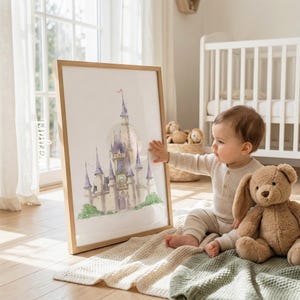 May include: A framed watercolor print of a fairy tale castle with tall purple spires and a clock face, displayed in a light wood frame. The artwork features soft pastel tones and detailed architectural elements, presented as a decorative wall piece.