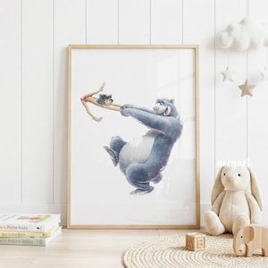 May include: A framed watercolor print featuring Baloo the bear and a young boy. Baloo, in shades of blue, is playfully holding the boy. The artwork has a light wood frame and is set against a white background, evoking a whimsical, storybook feel.