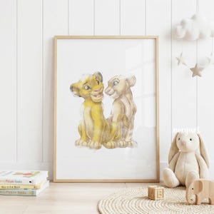 May include: Watercolor print of two lion cubs in a wooden frame. The cubs are depicted in shades of yellow and tan, with expressive faces. The artwork is displayed in a bright, airy room, suggesting a nursery or children's space.