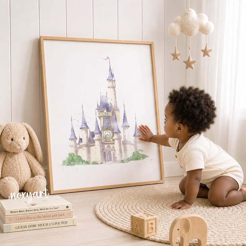 May include: A framed watercolor print of a castle with purple spires and a central clock tower. The artwork is displayed in a light wood frame. The print features soft, artistic brushstrokes and muted tones, depicting a classic fairy tale structure.