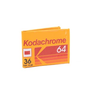 May include: A yellow Kodakchrome 36 exposure film cartridge with the text "Kodachrome 64" printed on the front.