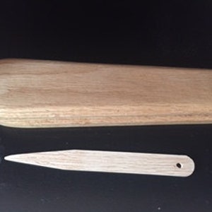 Può includere: Un calzascarpe in legno con un manico lungo e stretto e una punta arrotondata. Il calzascarpe è in legno marrone chiaro e misura circa 30 cm di lunghezza.
