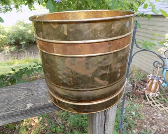 Een grote plantenbak of emmer van messing en koper met een koperen band rond de bovenkant