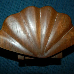 May include: A wooden box shaped like a seashell with a dark brown finish.