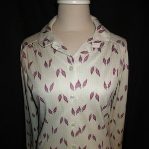 May include: A white button-down shirt with a leaf pattern in shades of red and blue. The shirt has a collar and long sleeves.