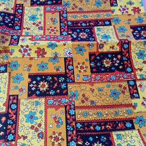 May include: A yellow fabric with a repeating pattern of colourful geometric shapes and floral designs. The fabric has a vintage look and feel.