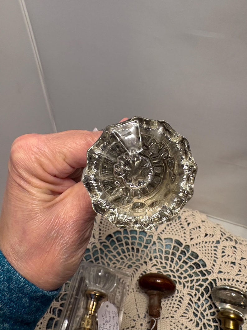 May include: A white ceramic mug with a black handle and the text "But First, Coffee" in a black, handwritten-style font. The mug is on a white surface.