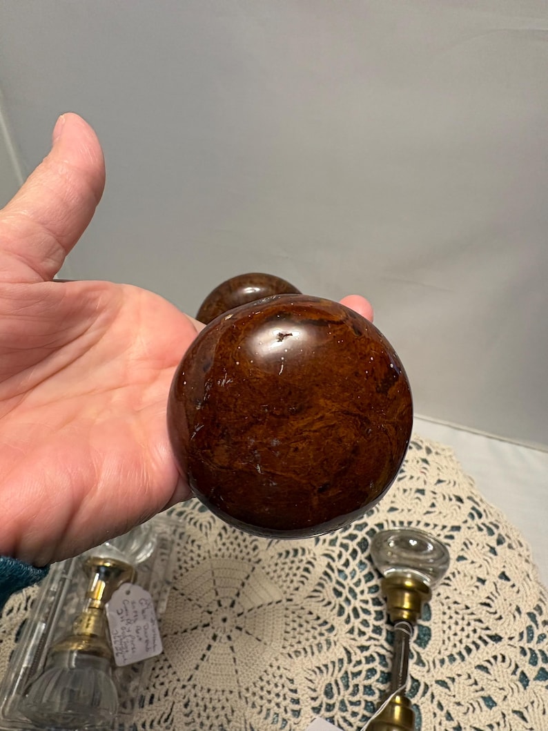 May include: A white ceramic mug with a black handle and the text "But First, Coffee" in a black, bold font. The mug is on a white surface. The mug is approximately 4 inches tall.