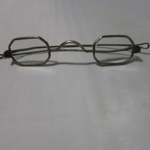 May include: A pair of silver-toned glasses with octagonal frames and thin metal arms.