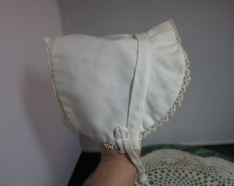 Vintage-Babyhaube aus weißer Baumwolle mit offener Rückenklappe und Knopf unten auf jeder Seite