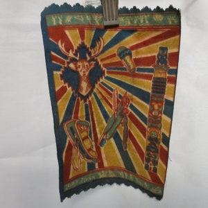 May include: A vintage fabric patch with a colorful design featuring a deer head, a totem pole, and other Native American-inspired motifs. The patch has a blue, red, yellow, and green color scheme.