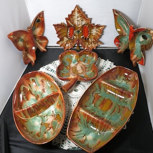 Puede incluir: Conjunto de seis platos de servir de cerámica vintage en un esmalte marrón, verde y naranja. Los platos presentan una mariposa, una hoja, un trébol y dos platos de servir divididos.