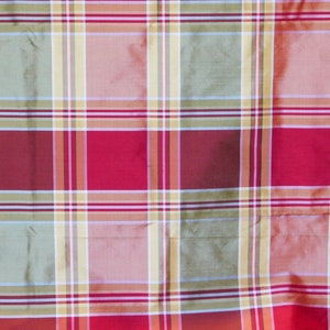 May include: A close-up of a plaid fabric with a repeating pattern of red, green, yellow, and white stripes. The fabric has a slight sheen, suggesting it may be silk or a similar material. The pattern is a classic plaid design.