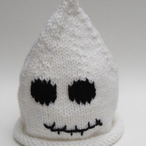 May include: White knitted ghost hat with black embroidered eyes and a stitched mouth.